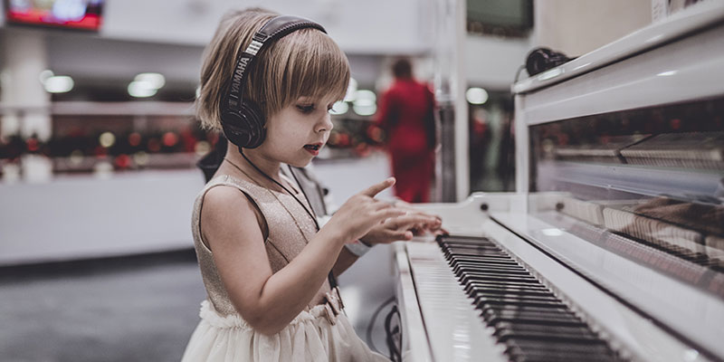 Niña con auriculares en piano con silenciador Silent System